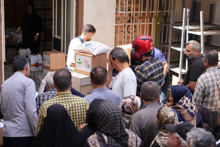 People waiting for boxes of food and essentials.